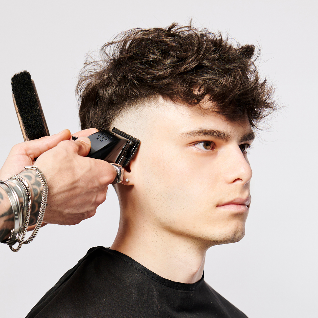 immagine di una parrucchiera che taglia i capelli ad un ragazzo, rasato nei lati